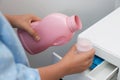 Woman pouring laundry detergent from bottle into cap near washing machine, closeup Royalty Free Stock Photo