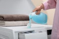 Woman pouring laundry detergent into cap on washing machine indoors Royalty Free Stock Photo