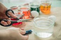 Woman pouring liquid orange Easter cold colour color in glass with water and vinegar next to green, yellow, red, blue dye in Royalty Free Stock Photo