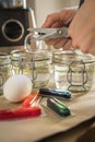 Woman pouring liquid red Easter cold colour color in glass with water and vinegar in domestic kitchen next to orange, yellow, Royalty Free Stock Photo