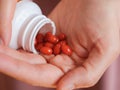 A woman pouring Lutein softgels out of a bottle into the palm of her hand