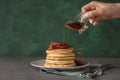 Woman pouring maple syrup onto tasty pancakes with fried bacon