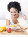 Woman pouring milk into a bowl of cereals to healthy breakfast o Royalty Free Stock Photo