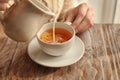 Woman pouring milk into cup with aromatic tea on table Royalty Free Stock Photo