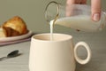 Woman pouring milk into cup at table, closeup Royalty Free Stock Photo