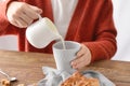 Woman pouring milk into cup of tea on table Royalty Free Stock Photo