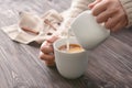 Woman pouring milk into cup of tea on table Royalty Free Stock Photo