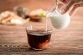 Woman pouring milk into glass cup with aromatic tea on table Royalty Free Stock Photo