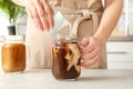 Woman pouring milk into mason jar with cold brew coffee