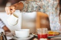 Woman pouring milk in mug from kettle Royalty Free Stock Photo