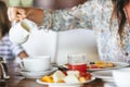 Woman pouring milk in mug from kettle Royalty Free Stock Photo