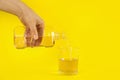 Woman pouring mouthwash into glass on yellow background, closeup