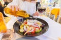 Woman pouring olive oil in greek fresh salad Royalty Free Stock Photo
