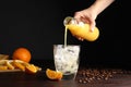 Woman pouring orange juice into glass with ice cubes at wooden table, closeup Royalty Free Stock Photo