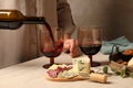 Woman pouring red wine into glass at wooden table, closeup Royalty Free Stock Photo