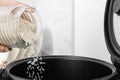 Woman pouring rice from jar into cooker in kitchen Royalty Free Stock Photo