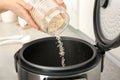 Woman pouring rice from jar into cooker in kitchen Royalty Free Stock Photo