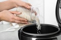 Woman pouring rice from jar into cooker in kitchen Royalty Free Stock Photo