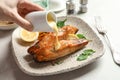 Woman pouring sauce onto tasty cooked salmon