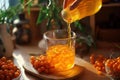 Woman pouring sea buckthorn juice from jug into glass Royalty Free Stock Photo