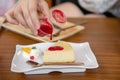 Woman pouring strawberry sauce to cheesecake Royalty Free Stock Photo