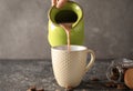 Woman pouring tasty cocoa from jug into cup on grunge table Royalty Free Stock Photo