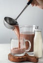 Woman pouring tasty cocoa with ladle into cup on white table Royalty Free Stock Photo