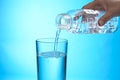 Woman pouring water from bottle into glass on background, closeup Royalty Free Stock Photo