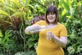 Woman pouring water from a bottle into a glass while standing in the garden. Happiness fat girl smiling in morning Royalty Free Stock Photo