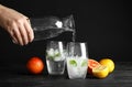 Woman pouring water into glass with ice cubes on table Royalty Free Stock Photo