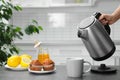 Woman pouring water from modern electric kettle into cup Royalty Free Stock Photo