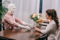 woman pouring wine into glass while sitting at table with layman doll unrequited Royalty Free Stock Photo