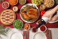 Woman pouring wine into glass at table with delicious roasted turkey for festive dinner