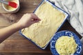 A woman pours cheese over raw uncooked pie. Wooden table, top view. Stages of preparation.