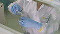 Woman pours clean liquid into lab galss above table