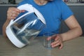 Woman pours clean water from a glass teapot into a glass beaker