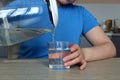 Woman pours clean water from a glass teapot into a glass beaker