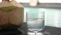 Coconut water pouring from fresh whole coconut into glass