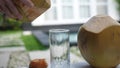 Coconut water pouring from fresh whole coconut into glass