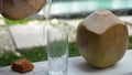 Coconut water pouring from fresh whole coconut into glass