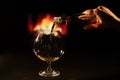 Woman pours cognac into a glass on the background of the fireplace.