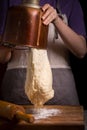A woman pours a dough out of a bowl of a breadmaker