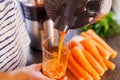 A woman pours fresh carrot juice into glass. Freshly squeezed carrot juice