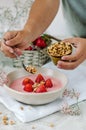 A woman pours homemade granola into a bowl of strawberry yogurt. Royalty Free Stock Photo