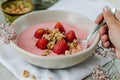 A woman pours homemade granola into a bowl of strawberry yogurt. Royalty Free Stock Photo