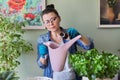 Woman pours liquid mineral fertilizer, in watering can with water