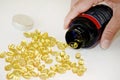 Senior adult woman pours out of the bottle in hand yellow capsules of omega 3, close-up.