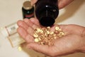Senior adult woman pours out of the bottle in hand yellow capsules of omega 3, close-up.