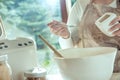 Woman pours salt into the dough for homemade bread