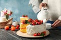 Woman pours tea on wooden table berry cream cake. Tasty dessert